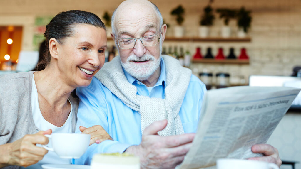 Due persone intente a leggere il giornale mentre fanno colazione