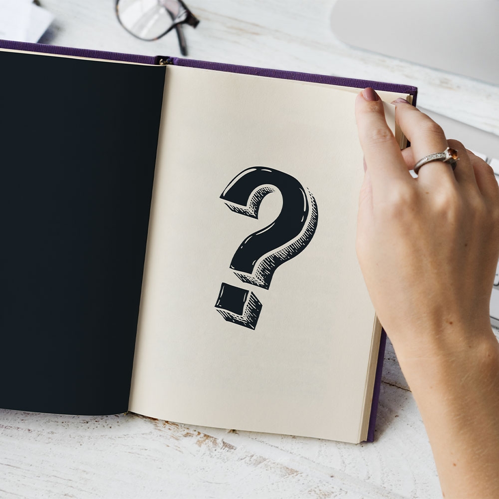 Mano intenta a sfogliare una pagina con un grande punto interrogativo disegnato